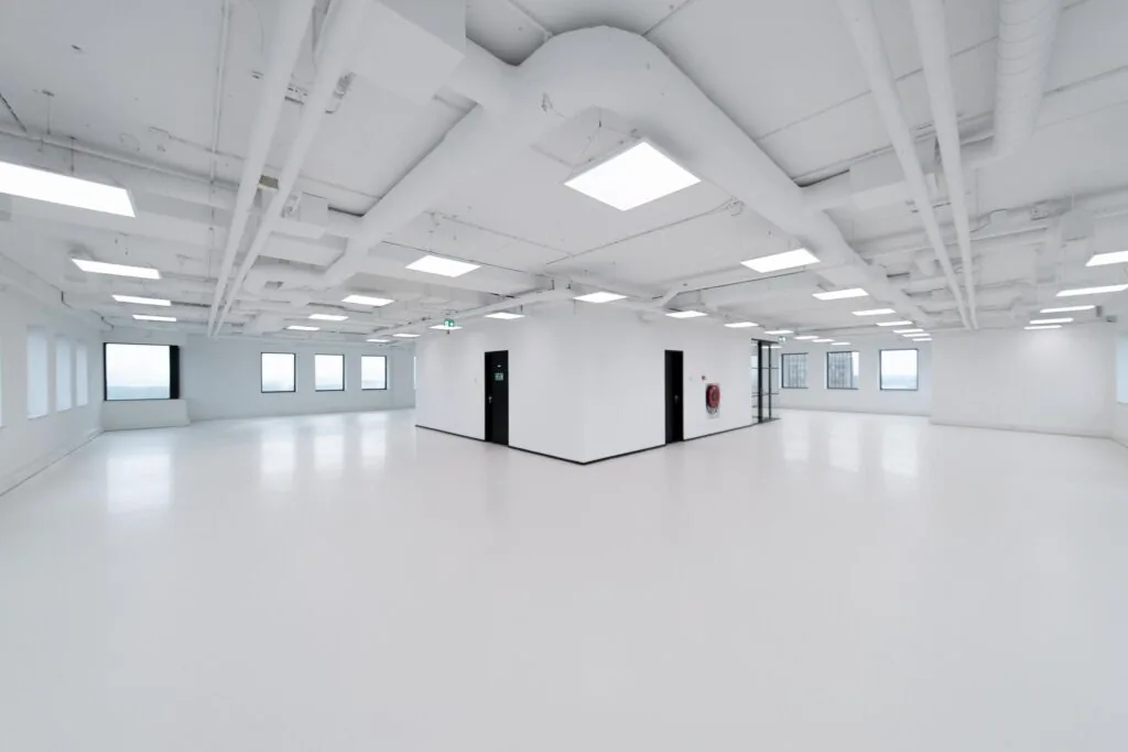 Licht en modern leeg kantoorpand in Rivium Quadrant met witte vloeren, plafonds en zichtbare leidingen.